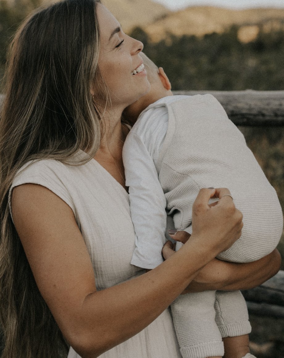 Ciara holding her child at golden hour, mid-laugh