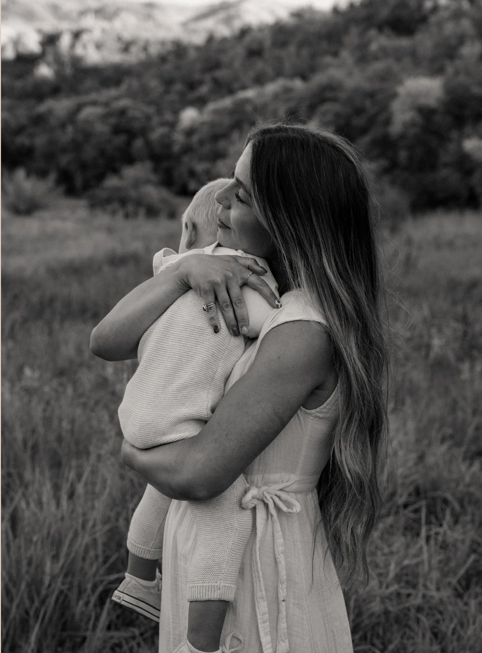 Ciara holding her child in a meadow, soft natural light